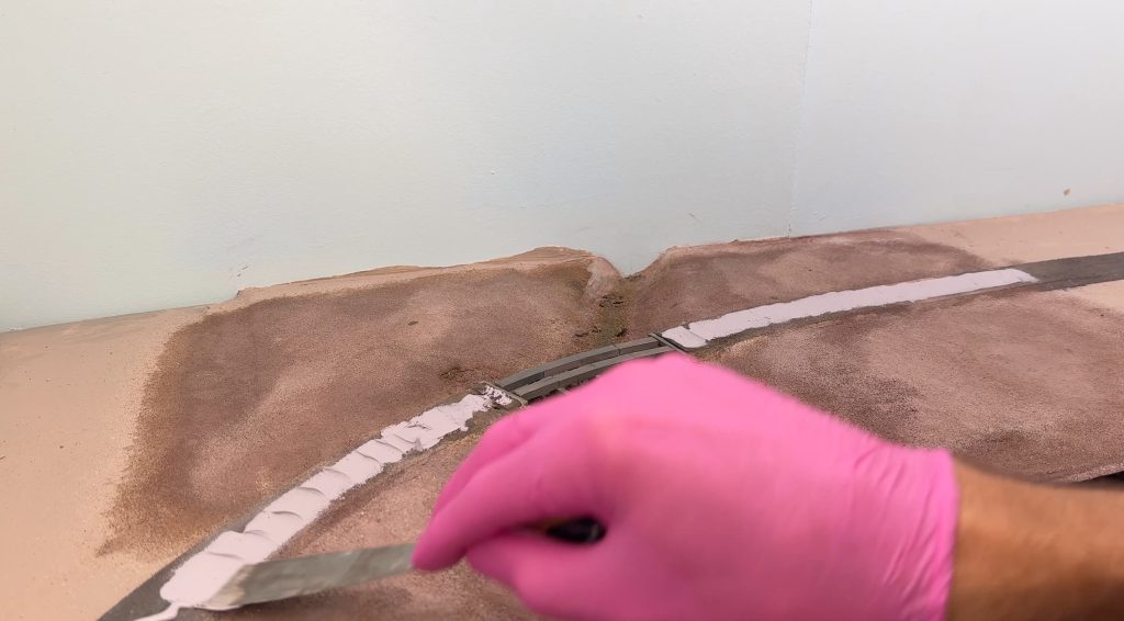 Bridge scenery: using caulk to glue flextrack in place.