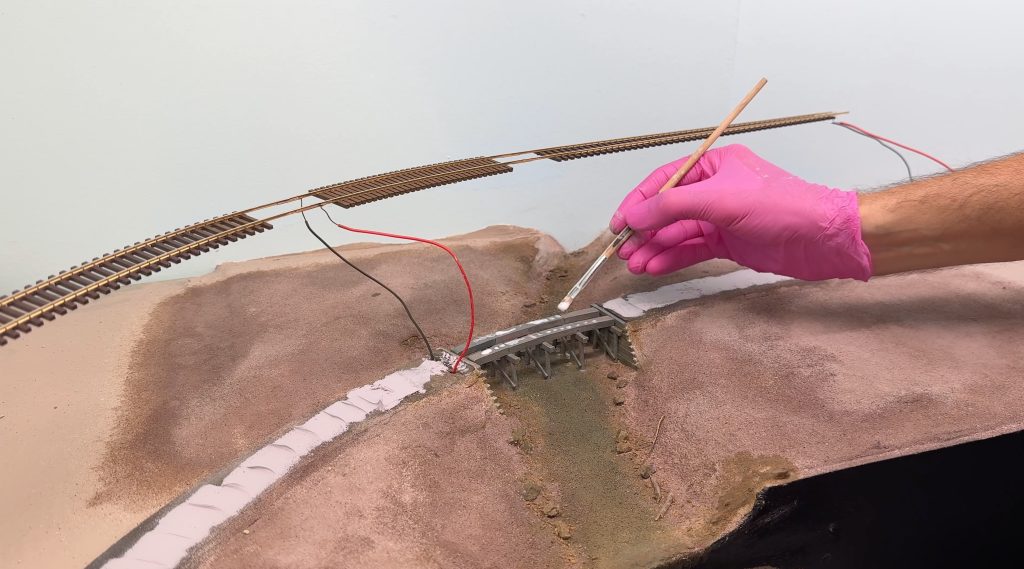 Bridge scenery: using matte medium to glue the bridge track in place.