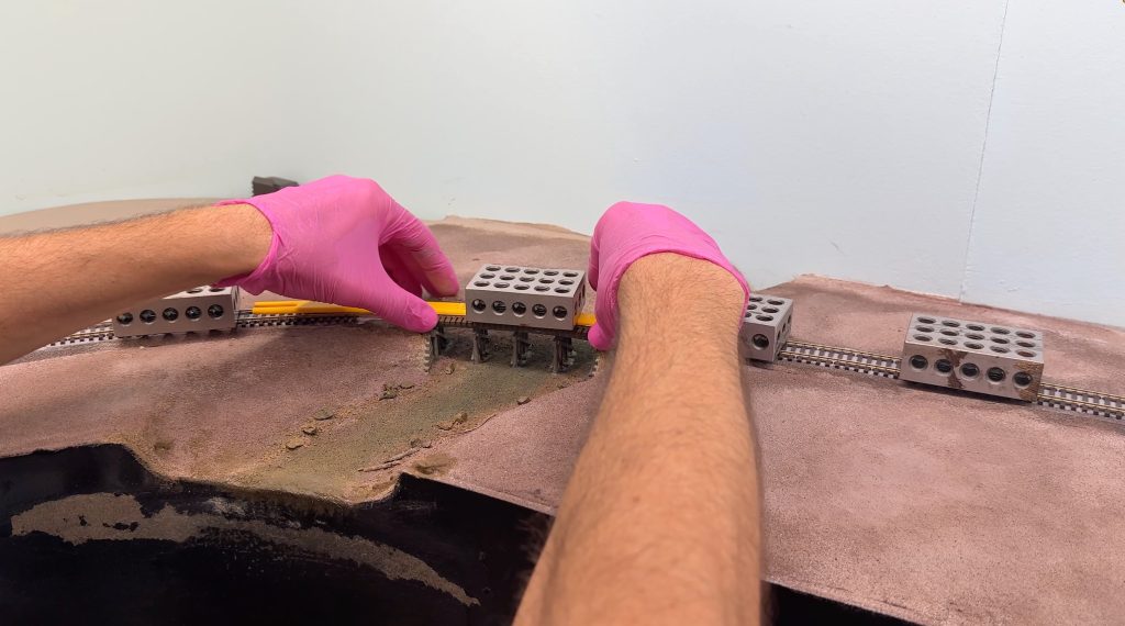 Adding weight and using the curved gauge to keep the flextrack in place while the glue dries.