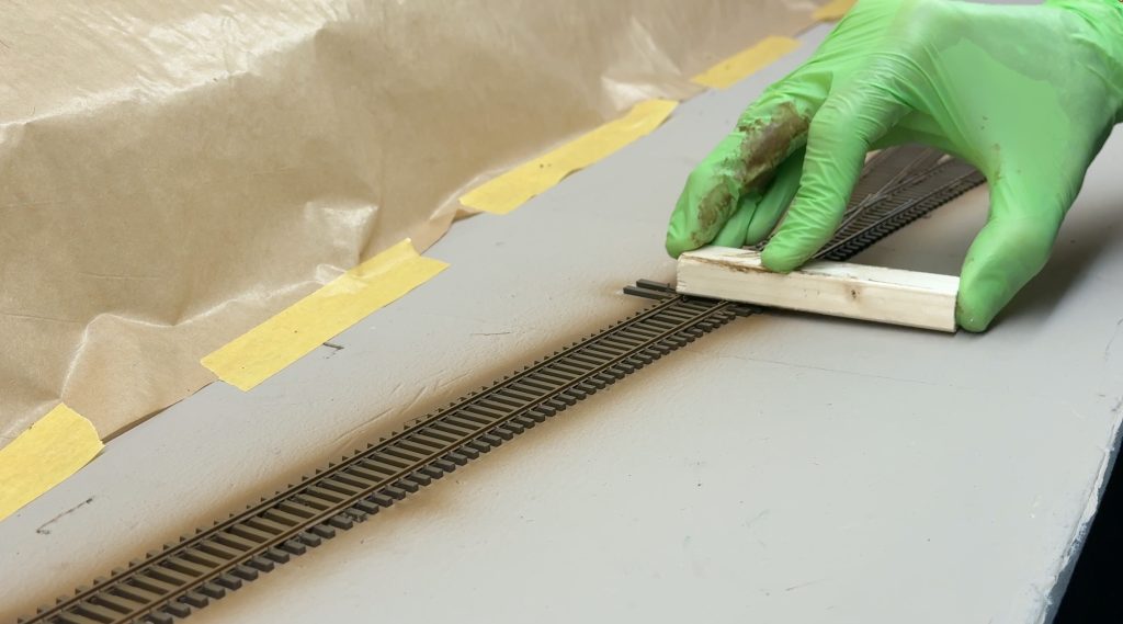 Cleaning the top of the rails with a wood block