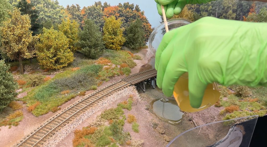 Bridge scenery: pouring the two-part epoxy resin on the riverbed.